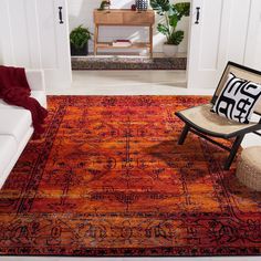 an orange and red rug in a living room with a chair on the floor next to it