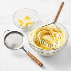 a bowl filled with mashed potatoes next to a strainer