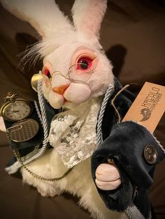 a white rabbit dressed up as a person holding an old fashioned pocket watch in its right hand