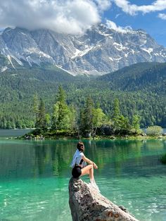 a person sitting on top of a log in the middle of a body of water