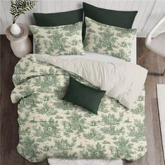 a bed with green and white comforters on top of wooden floor next to a potted plant