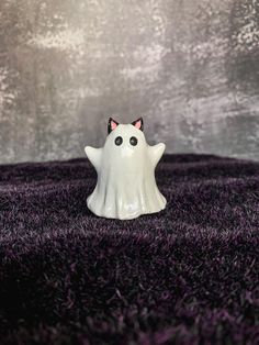 a white ghost figurine sitting on top of a purple carpet