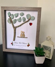 a wooden frame holding a paper cut out of a couple sitting on a tree swing