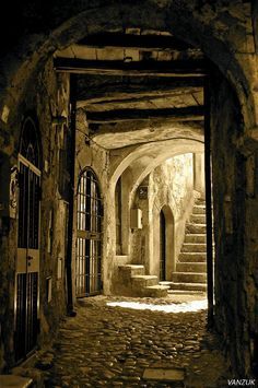 an alley way with stone steps leading up to the door and windows on either side