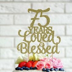 a white cake topped with a pink and blue frosted strawberry covered cake next to a brick wall