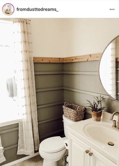 a white toilet sitting next to a bathroom sink under a round mirror in a bathroom