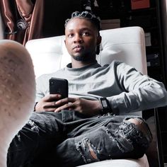 a man sitting in a chair holding a cell phone