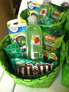 a green basket filled with lots of different types of snacks and drinks on top of a counter