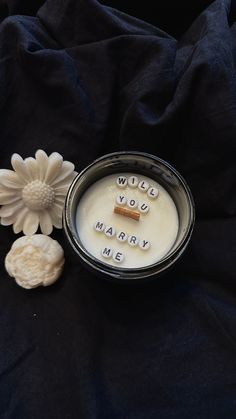 a candle with words written on it next to a flower and two small soaps