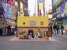 people are sitting on benches in the middle of a street with billboards behind them