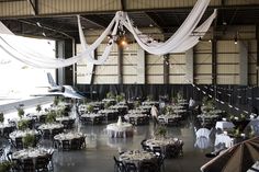 an airplane is flying in the air above tables and chairs with white draping