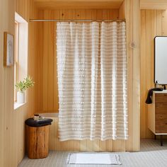 a bathroom with wood paneled walls and a white shower curtain hanging from the ceiling