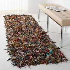 a rug made out of newspaper strips on the floor with a bench in the background