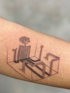 a person with a tattoo on their arm that has an image of a man sitting at a table