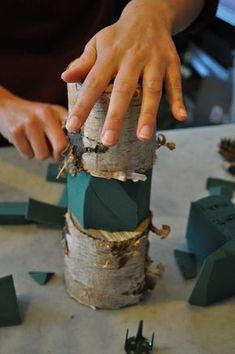 a person is working on something made out of tree trunks and wood sticks with their hands