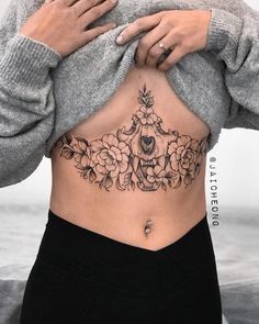 a woman's stomach has a tattoo on it and is holding her hands behind her back