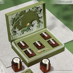 an open box with four different types of jams in it and two small jars next to each other