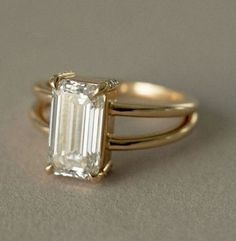 an engagement ring with a large emerald cut diamond in the center and two thin bands around it