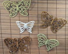 four butterflies are sitting on a bamboo mat, one is green and the other is white