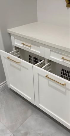 a white kitchen cabinet with two baskets in the bottom and an open drawer on top