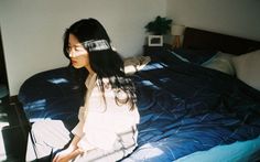 a woman sitting on top of a bed next to a laptop computer