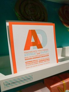 an orange and white business card sitting on top of a shelf next to other items