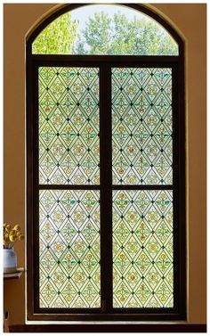 a stained glass window in the corner of a room with a potted plant next to it