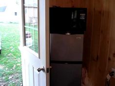 a black refrigerator freezer sitting inside of a wooden wall next to a white door