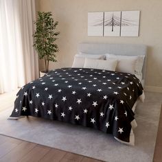 a black and white bedspread with stars on it is in a bedroom next to a potted plant