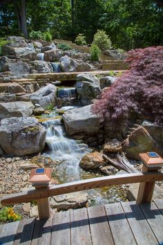 a wooden bench sitting next to a small waterfall