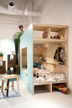 a person standing on top of a bed next to a shelf filled with books and toys