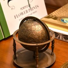 an old metal globe sitting on top of a wooden table next to a green book