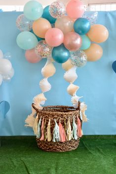 a basket filled with balloons and tassels sitting on top of a green carpet