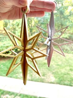 someone is holding an ornament made out of wood and paper stars in their hand