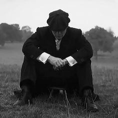 a man sitting in the grass with his hands on his knees