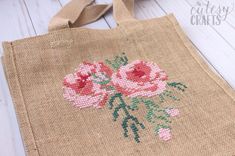 a bag with pink flowers on it sitting on a white wooden floor next to a pair of scissors