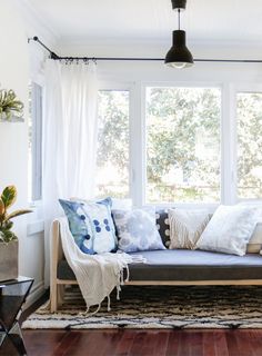 a living room filled with furniture and lots of window sill space next to a wooden floor