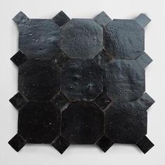 a black tile wall hanging on the side of a white wall