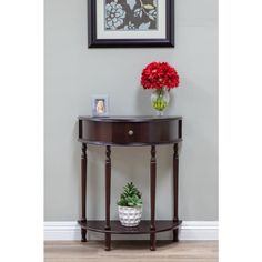 a vase with red flowers sitting on top of a wooden table next to a wall