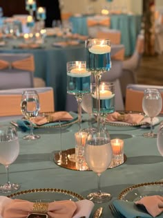 the table is set with wine glasses, plates and candles for an elegant dinner party