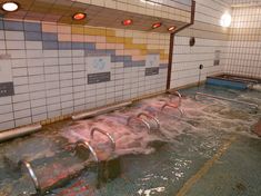 an indoor swimming pool with no people in it and several ladders on the side