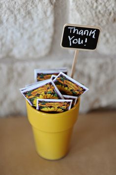 a yellow cup filled with stickers sitting on top of a table next to a sign that says thank you