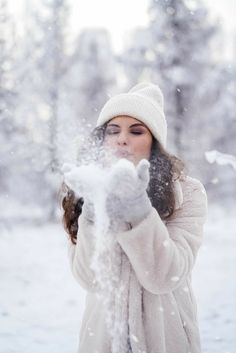 a woman blowing snow with her hands