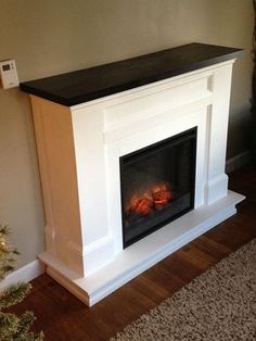 a fire place in the corner of a room with a christmas tree on the floor