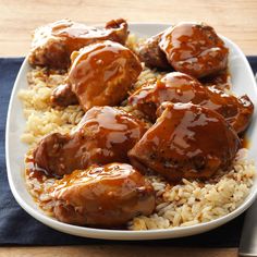 a white plate topped with meat covered in gravy next to rice and a fork