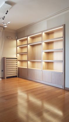 an empty room with wooden floors and built in bookshelves