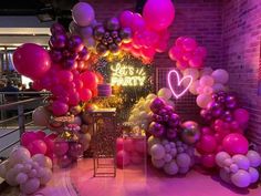 balloons and streamers decorate the entrance to a party with pink, purple, and white colors