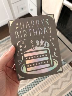 a person holding up a card with a cake on it that says happy birthday in front of a stove