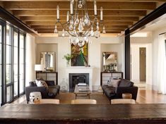 a living room filled with furniture and a chandelier hanging from the ceiling over a fire place