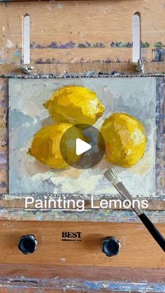 the painting lemons is being displayed in front of an easel with paintbrushes